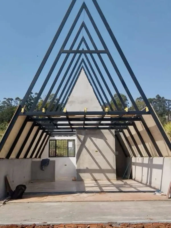 Estrutura metálica A-frame em construção com paredes brancas